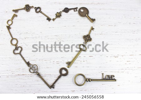 Heart shape made with old antique keys. Valentines day concept on a white distressed wood background.