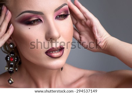 Beautiful girl with dramatic evening  burgundy makeup. Beauty face. Picture taken in the studio on a grey background.