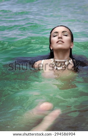 Beautiful girl brunette in green lake swimming in clothes