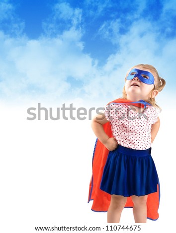 A young girl is dressed up as a superhero and looking up in the sky with a mask and cape. There is a copyspace to add a message area. Use it for a strength or halloween concept.