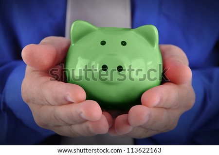 A business man is holding a bright green piggy bank in his hands for a money or finance concept.