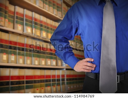 A consultant man is standing in front of a law library of books with copy space area. Use it for a attorney or education concept.