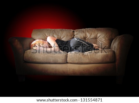 A girl is laying down on a couch sad with depression and body ache\'s for a pain concept. There is a black isolated background.