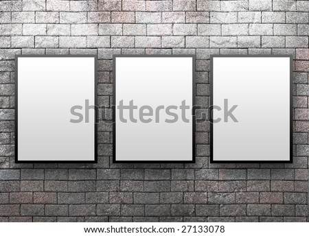 Three blank, white canvas frames are hanging on a brick wall. Light is shining down on them.