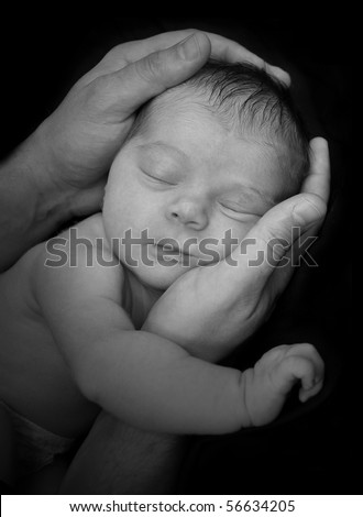 A father is holing a baby newborn in his hands. The infant is sleeping and it is a black and white portrait. The image can represent security, innocence or parenthood.