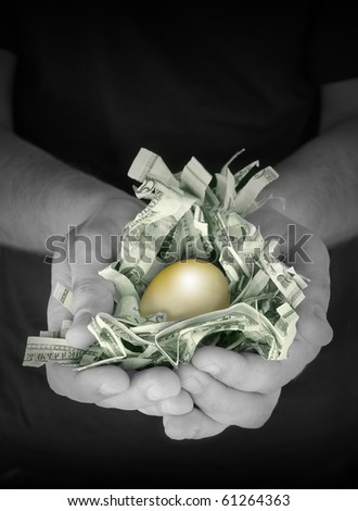A man is holding a golden nest egg. There is shredded american money and a gold egg on top. Use it for a savings, financial security or retirement concept.