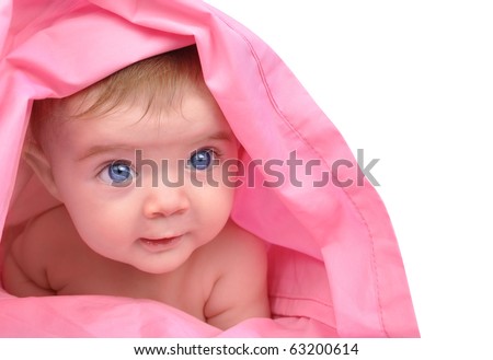 A cute little baby girl is staring up and is hiding under a pink sheet blanket. She is isolated on a white background. Add your text to the right side. Use it for a child, parenting or love concept.