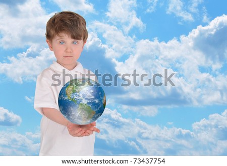 A young boy is holding the planet Earth in his hands and looks serious. There is a bright blue sky in the background and copyspace for text.