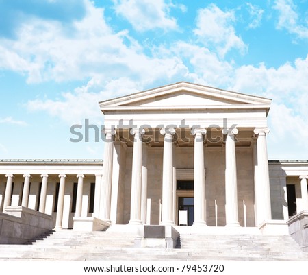 A city courthouse law building with pillar columns and stairs. Bright clouds are in the background. Can represent law, justice or legislation.