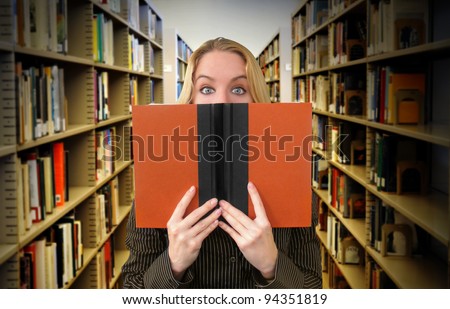 A woman is reading a book in the library and looks surprised. Use it for an education or academic concept.