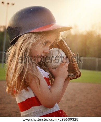 A little child is playing a game of baseball on the dirt field with a glove mitt on for a sport or recreation concept.