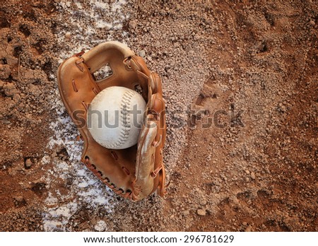 A closeup of an old baseball and glove on a dirt background with copyspace for a message for a sport or recreation concept.