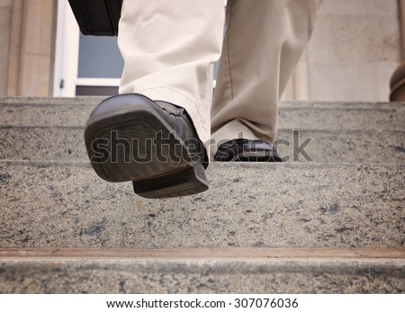 A business man is stepping down the stairs at an office for a power, challenge or motivation concept.