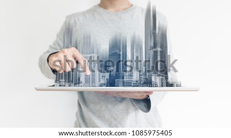 a man using digital tablet, and modern buildings hologram. Real estate business and building technology concept