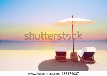 Tropical beach in sunset with beach chairs and umbrella