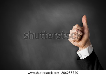 thumbs up in front of black chalkboard