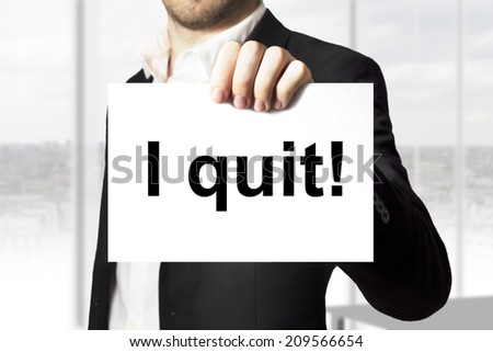 businessman in office holding sign i quit