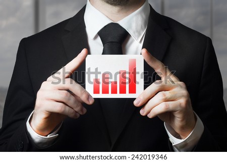 businessman in black suit holding sign red bar diagram