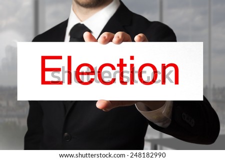 businessman in black suit holding sign election