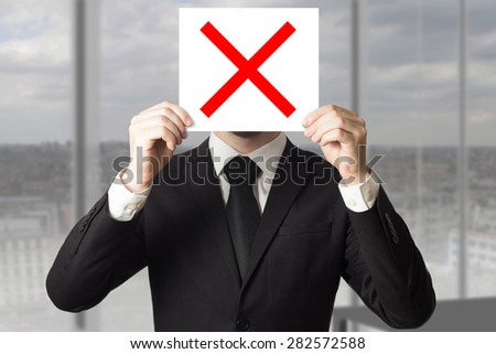 businessman hiding face behind red sign crossed out