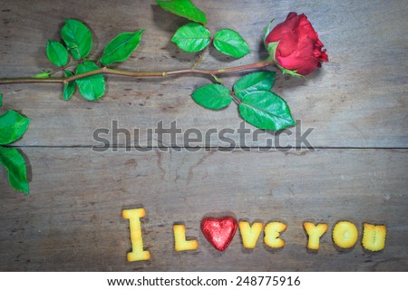 Happy Valentine\'s Day red roses on dark recycled wood background with word I Love You dessert