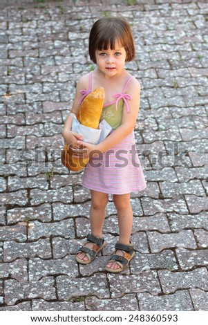 Cute little girl holding a loaf of bread