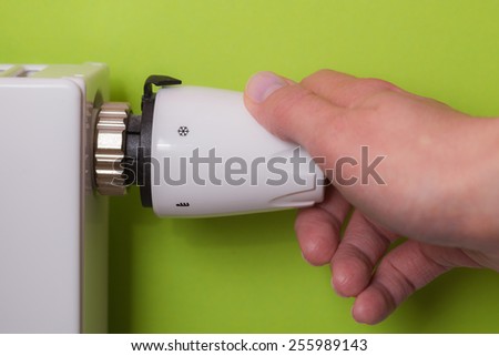 Closeup of a woman\'s hand setting the room temperature By Thermostat