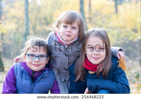 Happy Siblings - Three sisters in the autumnal forest smiling and hugging