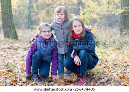 Happy Siblings - Three sisters in the autumnal forest smiling and hugging