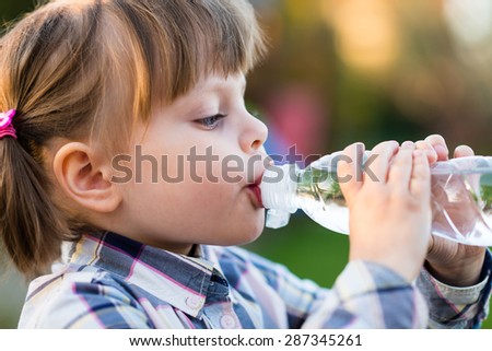 Girl Drinking Water. Portrait of cute little girl drinking water outdoor - very shallow depth of field (girl\'s eye is perfectly sharp)