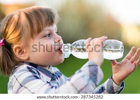 Girl Drinking Water. Portrait of cute little girl drinking water outdoor - very shallow depth of field (girl\'s eye is perfectly sharp)