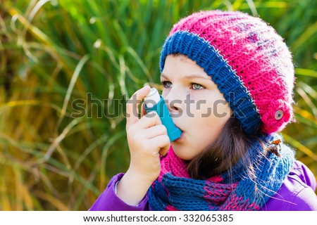 Girl Using Inhaler on an autumn day - to Treat Asthma Attack. Inhalation treatment of respiratory diseases. Shallow depth of field. Allergy concept. Asthma child