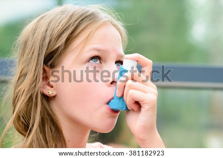Girl having asthma allergy using the asthma inhaler for being healthy - shallow depth of field