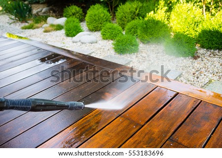 cleaning terrace with a power washer - high water pressure cleaner on wooden terrace surface