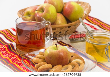 Glass cup of tea with lemon, basket of apples, honey and bagels
