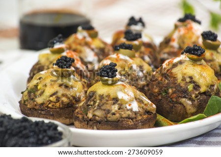Stuffed white mushrooms with green olives, cheese and black caviar