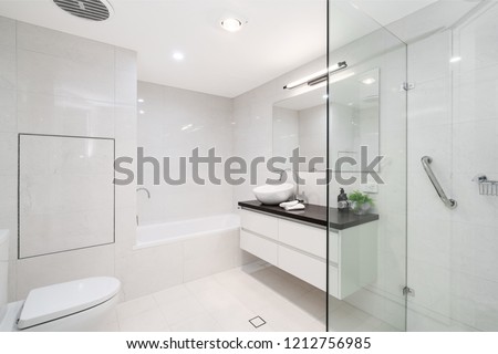 Large modern bathroom interior with floor to ceiling tiling and luxury fittings.