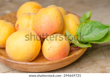 Beautiful wooden bowl full of ripe apricots with a rustic background.