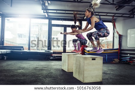 Fitness woman doing box jump workout at gym. Female athletes doing box jump workout at gym.
