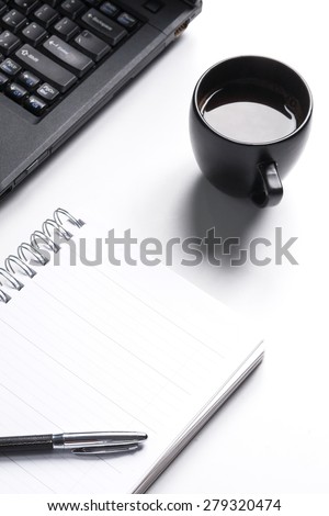 White paper blank notebook on the computer white desk. Lap top is black. Black coffee is on desk./White paper notebook on white desk