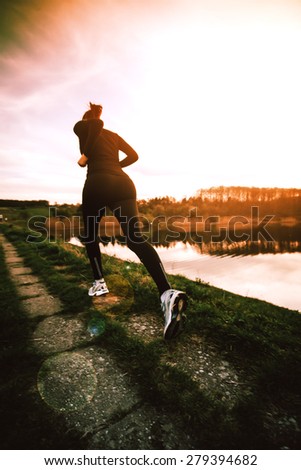 Young woman athlete running in nature at the sunrise