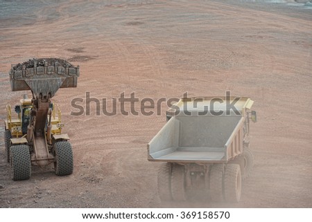 excavator loading a dumper truck with construction material stones. quarry. mining industry.
