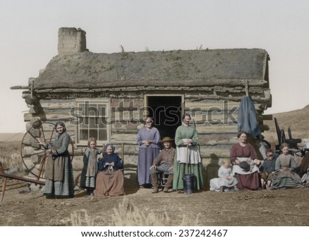 Mormon family portrait One man five women and four children pose front of their small log cabin in the Great Salt Lake Valley.