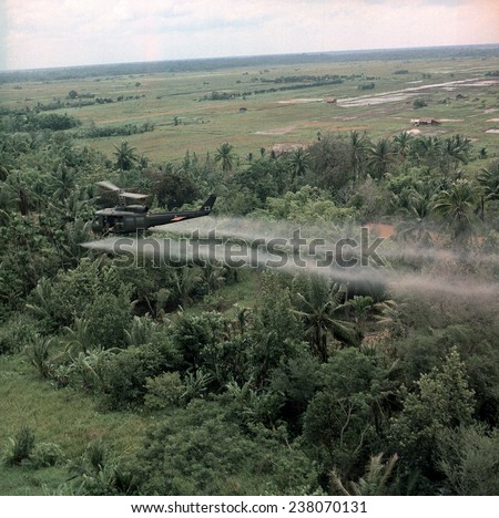 Vietnam War Defoliation Mission a UH- 1D helicopter from the 336th Aviation Company sprays a agent orange on a dense jungle area in the Mekong delta