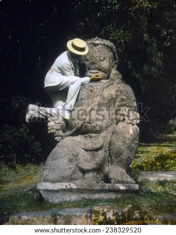 Indonesia, man in straw hat standing on Buddhist idol at ruins of Borobudur, hand colored lantern slide, photograph by William Henry Jackson, 1895.