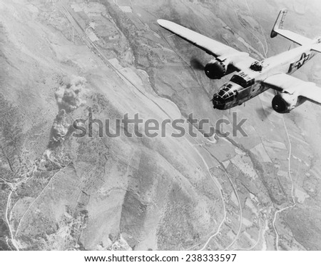 World War II, a Nazi supply dump goes up in smoke. A U.S. B-25 medium bomber roars over Tivoli, Nazi supply center ten miles east of Rome. Italy, photograph, 1940-1946.
