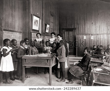 African American children learning about Thanksgiving, with model log cabin on table, Whittier Primary School, Hampton, Virginia. Ca. 1899.