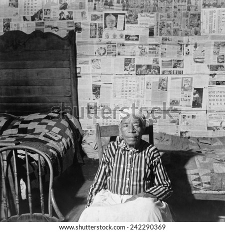 Elderly former slave in her sitting in her news papered home in May 1941. The beds are covered with handmade quilts. Greensboro, Alabama, May 1941.