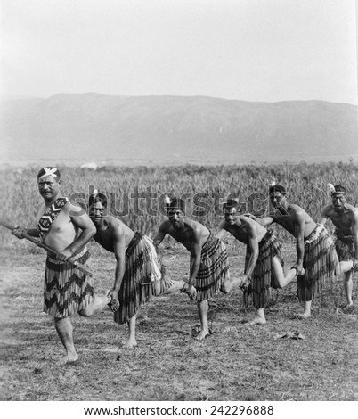 Five Maori men posing in traditional clothing doing haka dance. The dance of the New Zealand natives employs facial distortions to enhance dance expression. Ca. 1905.