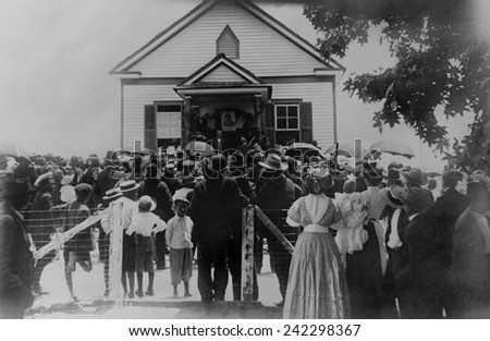Booker T. Washington addressing crowd from porch of a small building, in Brownsville, Texas, ca. 1900.